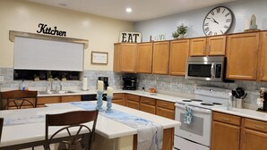 Una cocina con armarios de madera, un microondas de acero inoxidable, una estufa y un reloj en la pared.