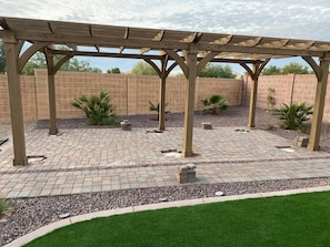 A covered patio area with a brick floor and a pergola structure.