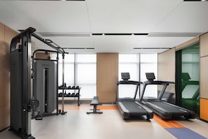 A gym with treadmills, a weight machine, and dumbbells.