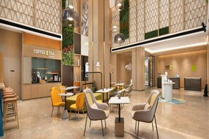 Un espacio interior moderno con zonas de estar, una cafetería y un mostrador de recepción.