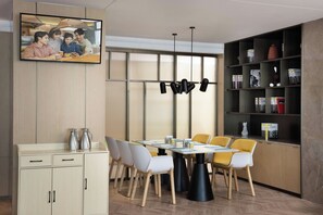 Un comedor moderno con un armario de madera, un televisor montado en la pared y una estantería llena de libros y revistas.
