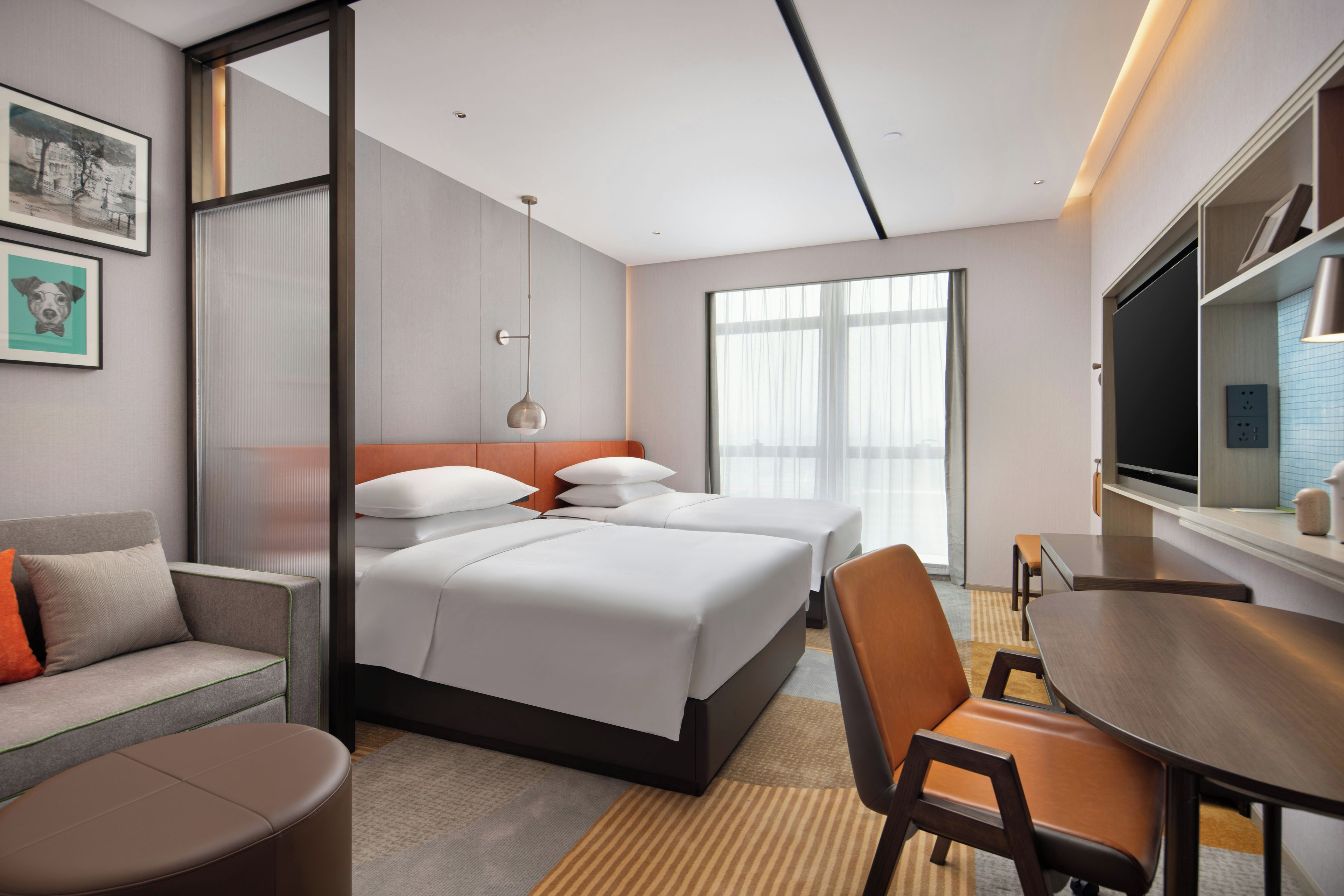 Een moderne hotelkamer met een bed, een bureau, een stoel, een bank en een televisie.