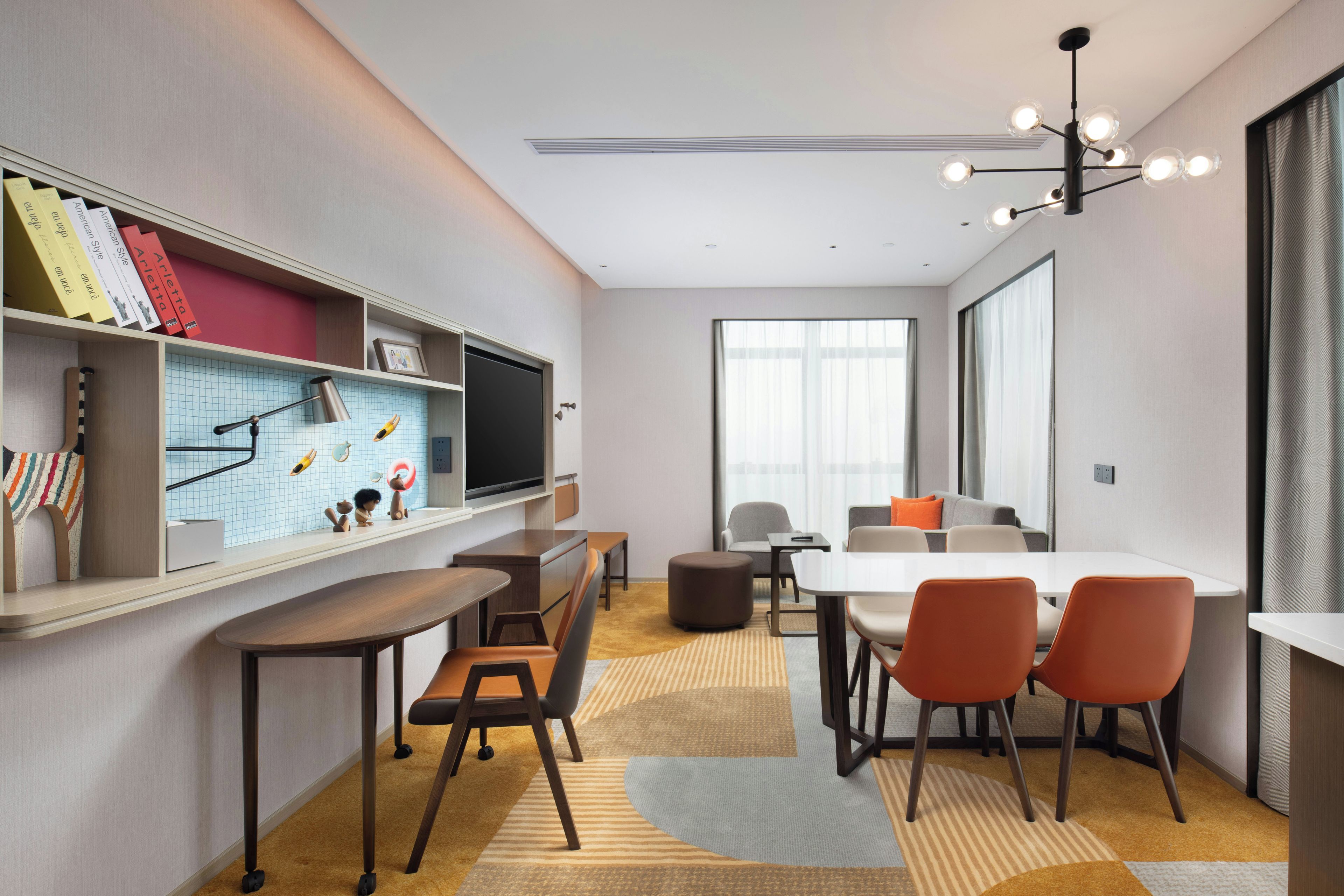 A modern meeting room with a long table, chairs, a television, and a bookshelf.