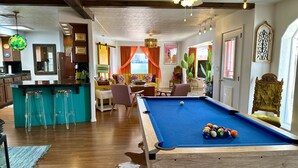 Un salon chaleureux avec une table de billard, un coin bar et un espace repas.