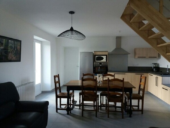 A modern kitchen with wooden cabinets, a built-in oven, and a hanging light fixture.