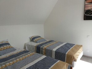 A bedroom with two single beds, each with patterned bedding and pillows. - A vacation rental between the sea and the countryside   (Sibiril)