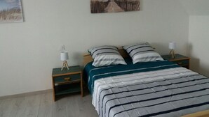 Een slaapkamer met een bed, twee nachtkastjes, een lamp en een schilderij aan de muur.