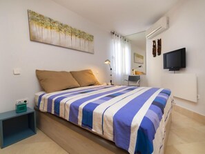 Ein Schlafzimmer mit einem Bett, einem Nachttisch, einem Fernseher und einem Bild an der Wand.