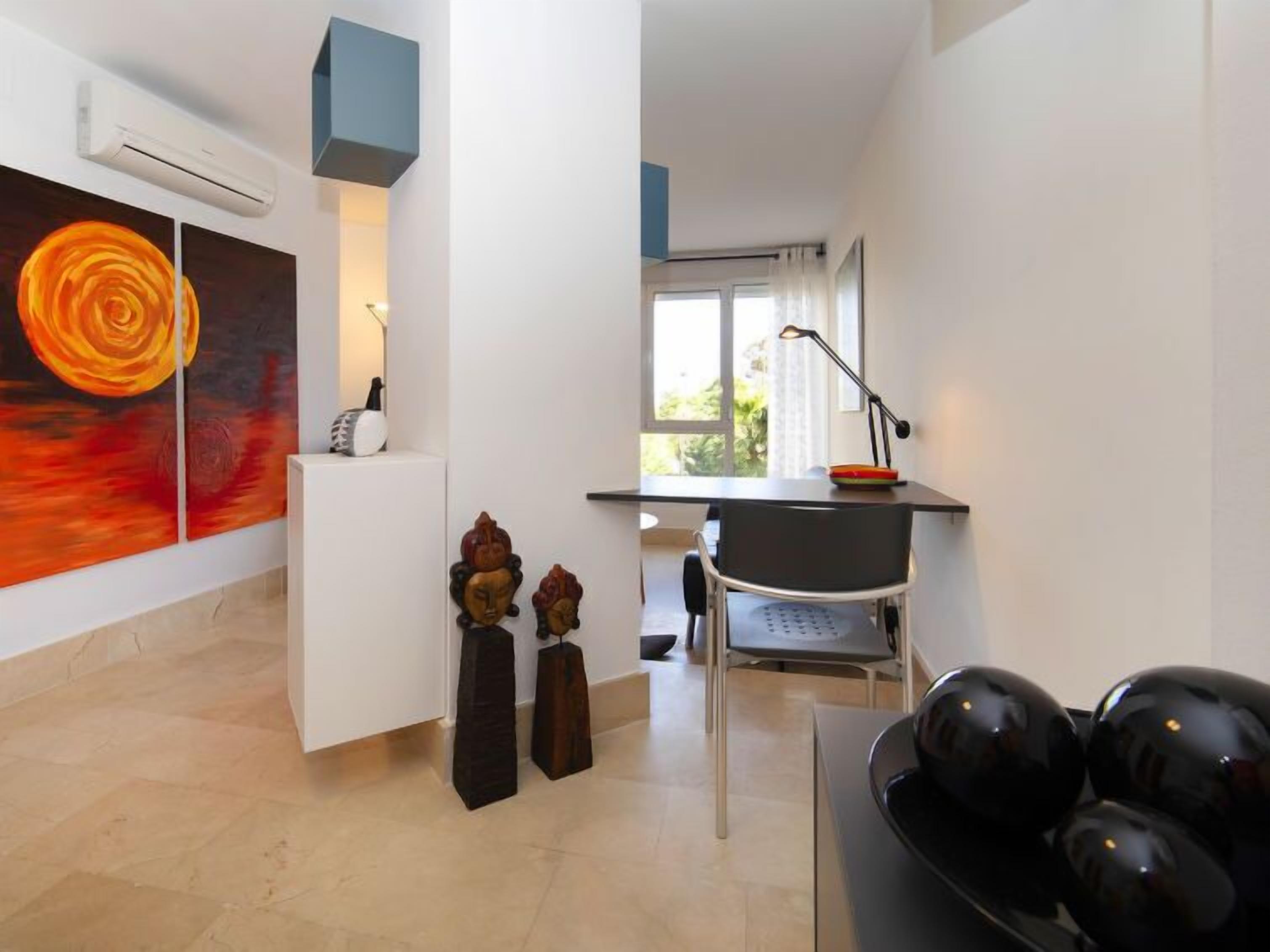 Une chambre moderne équipée d’un bureau, d’une chaise et d’un grand tableau abstrait.