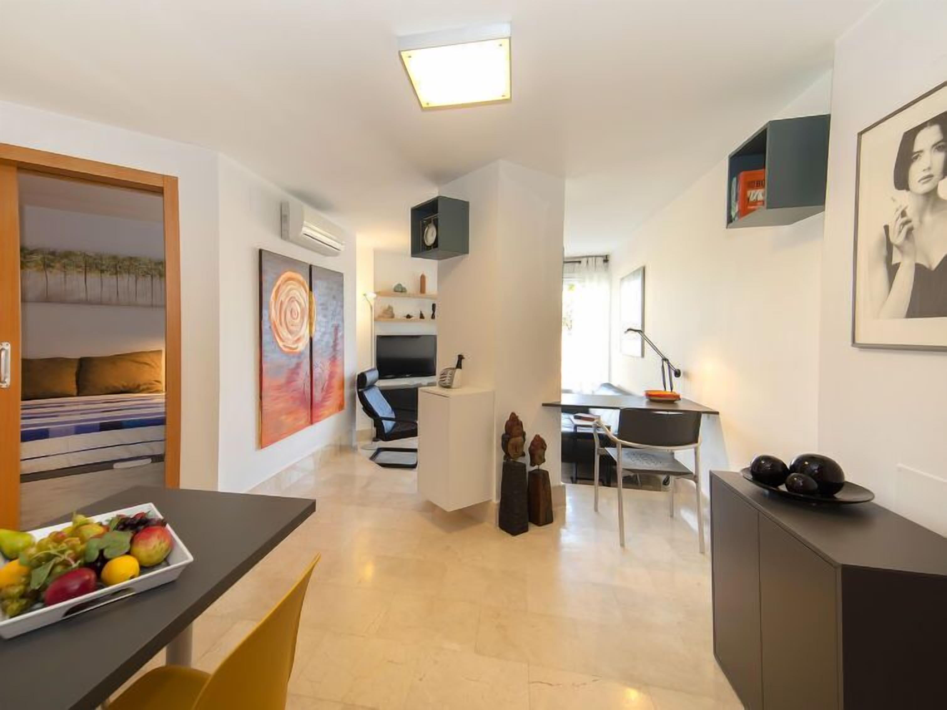 A modern living room with a dining area, a TV, and a fruit bowl on the table.