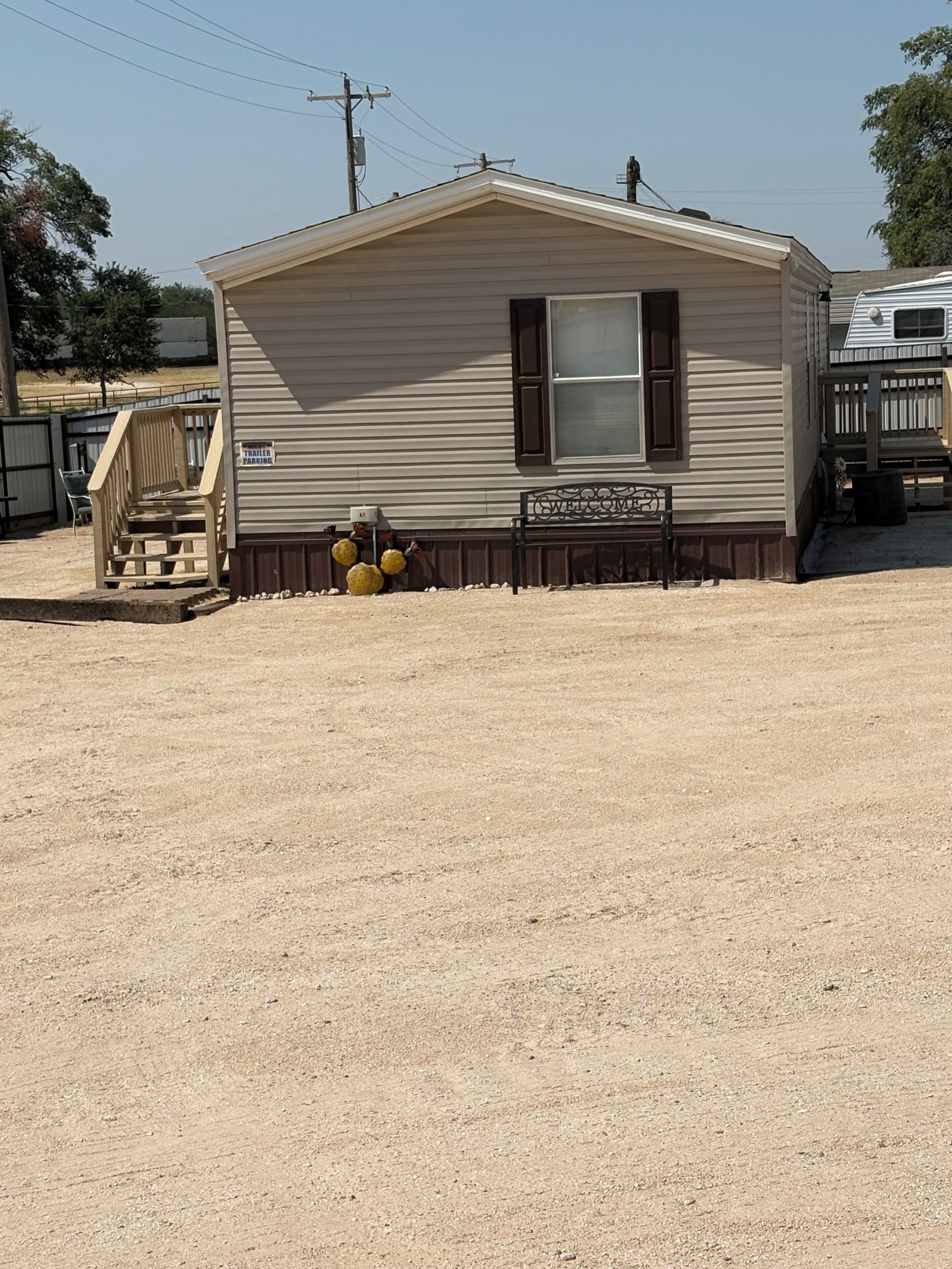 A single-story mobile home with a front porch and a 'Welcome' sign.