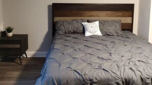 Une chambre à coucher avec un lit, une table de chevet ornée d’une plante et un mur décoré de trois tableaux.