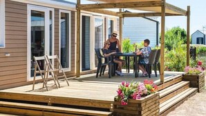 Eine Holzterrasse mit einer Pergola, Sitzgelegenheiten im Freien und Blumenkästen.