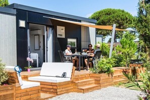 Relax in a serene outdoor space surrounded by lush greenery and a pergola, featuring a comfortable bench and table.