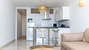 Une cuisine moderne avec des armoires blanches, un plan de travail en acier inoxydable et un luminaire suspendu.