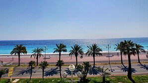 A coastal road with palm trees, a beach, and a clear blue sky. - N&J - BLUE PROMENADE - Sea front - central - Luxe (Niza)