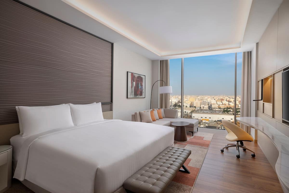 Une chambre d’hôtel moderne avec un grand lit, un canapé, une petite table et une vue sur la ville.