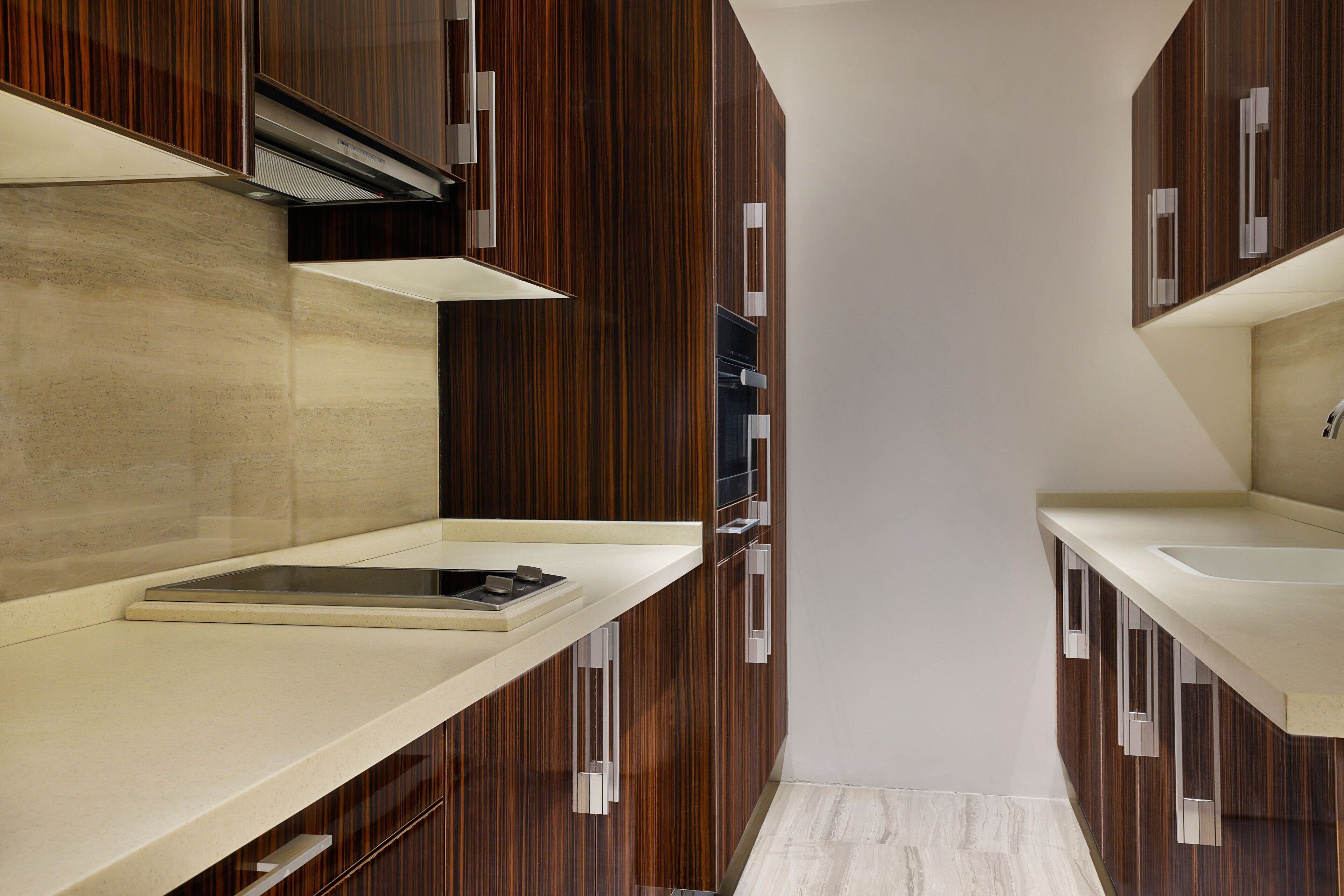 Una cocina moderna con armarios de madera, encimeras blancas y una estufa integrada.