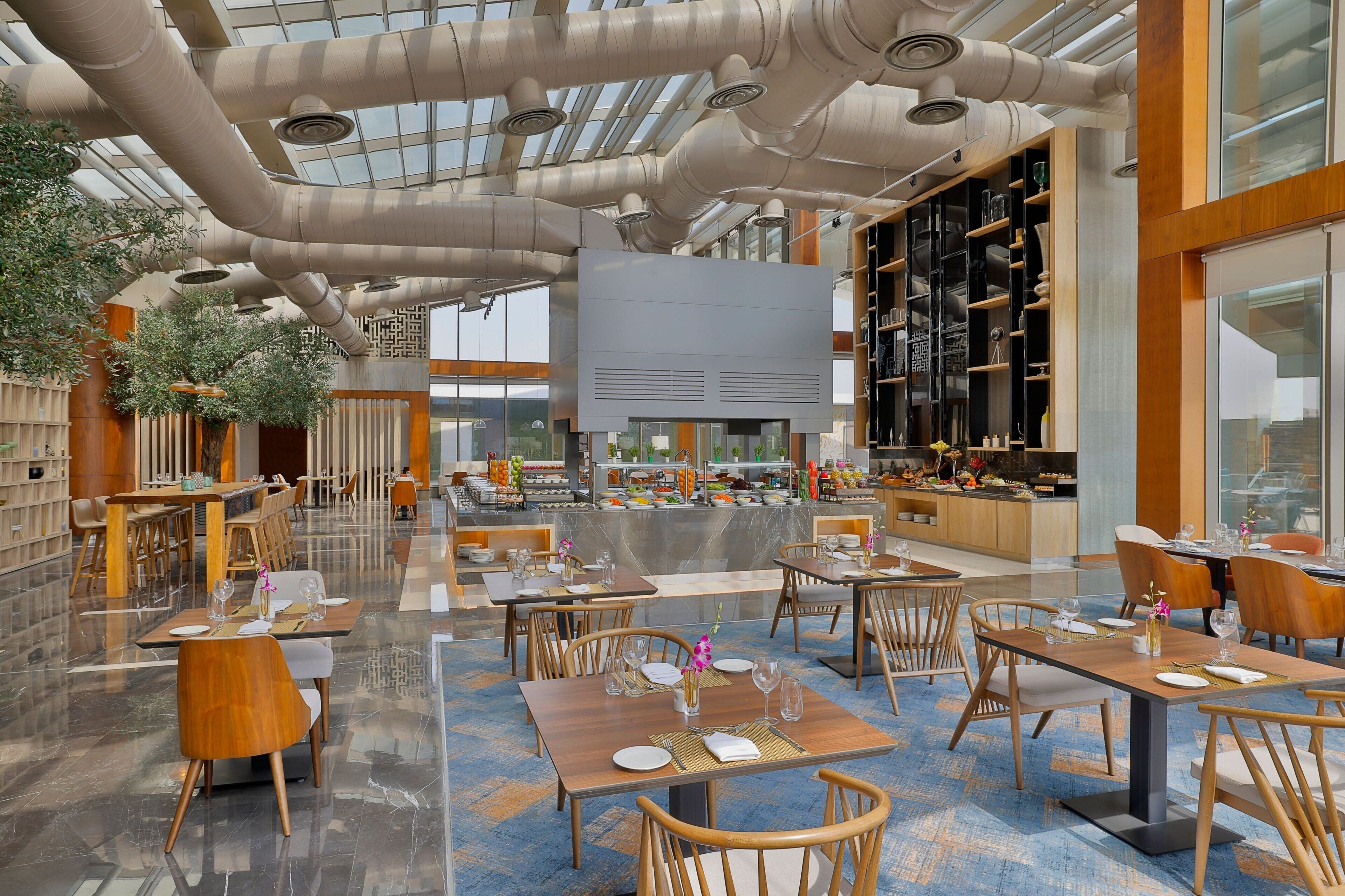A spacious restaurant with high ceilings, exposed ductwork, and a variety of seating arrangements.