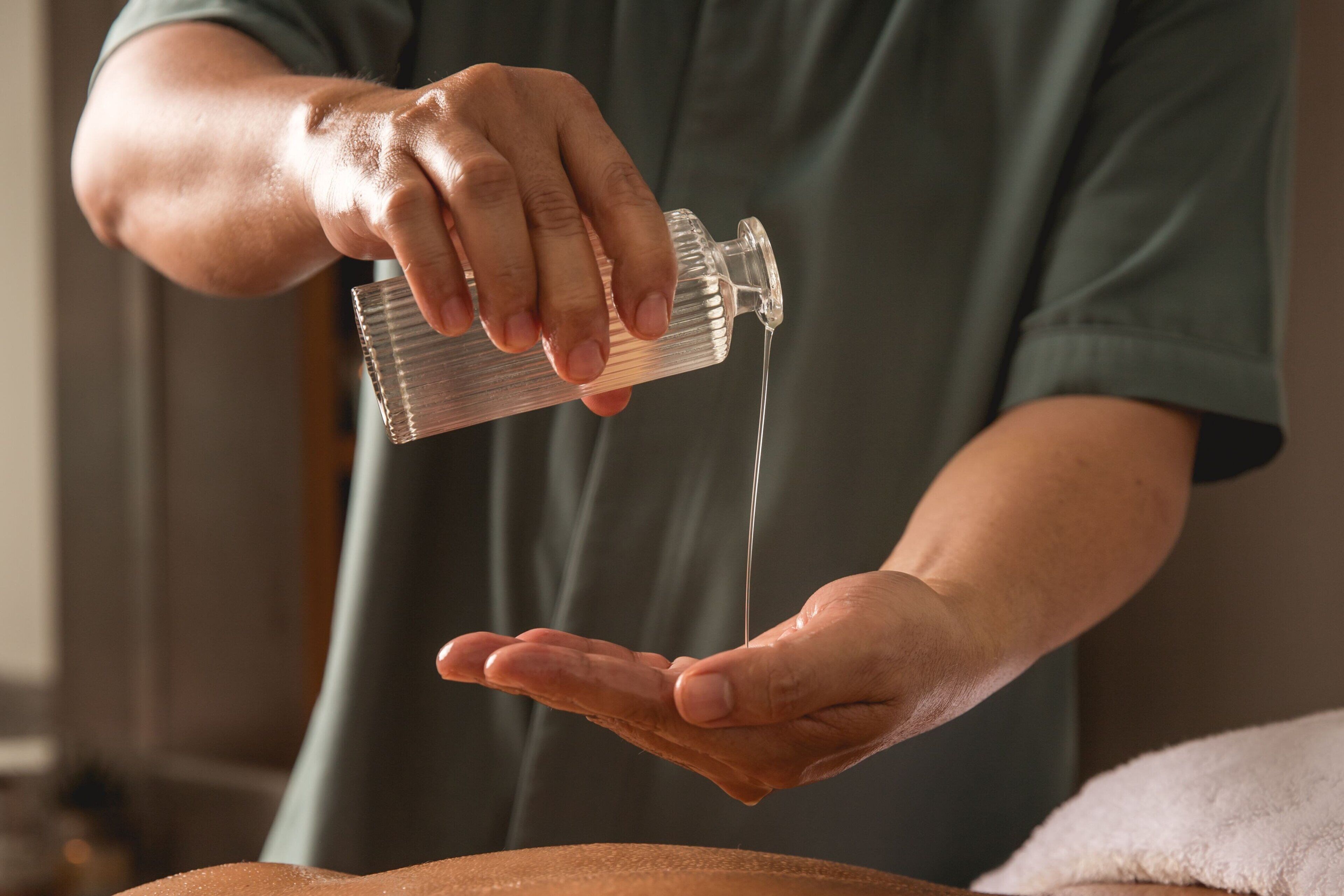 A person pouring liquid from a bottle into their hand.