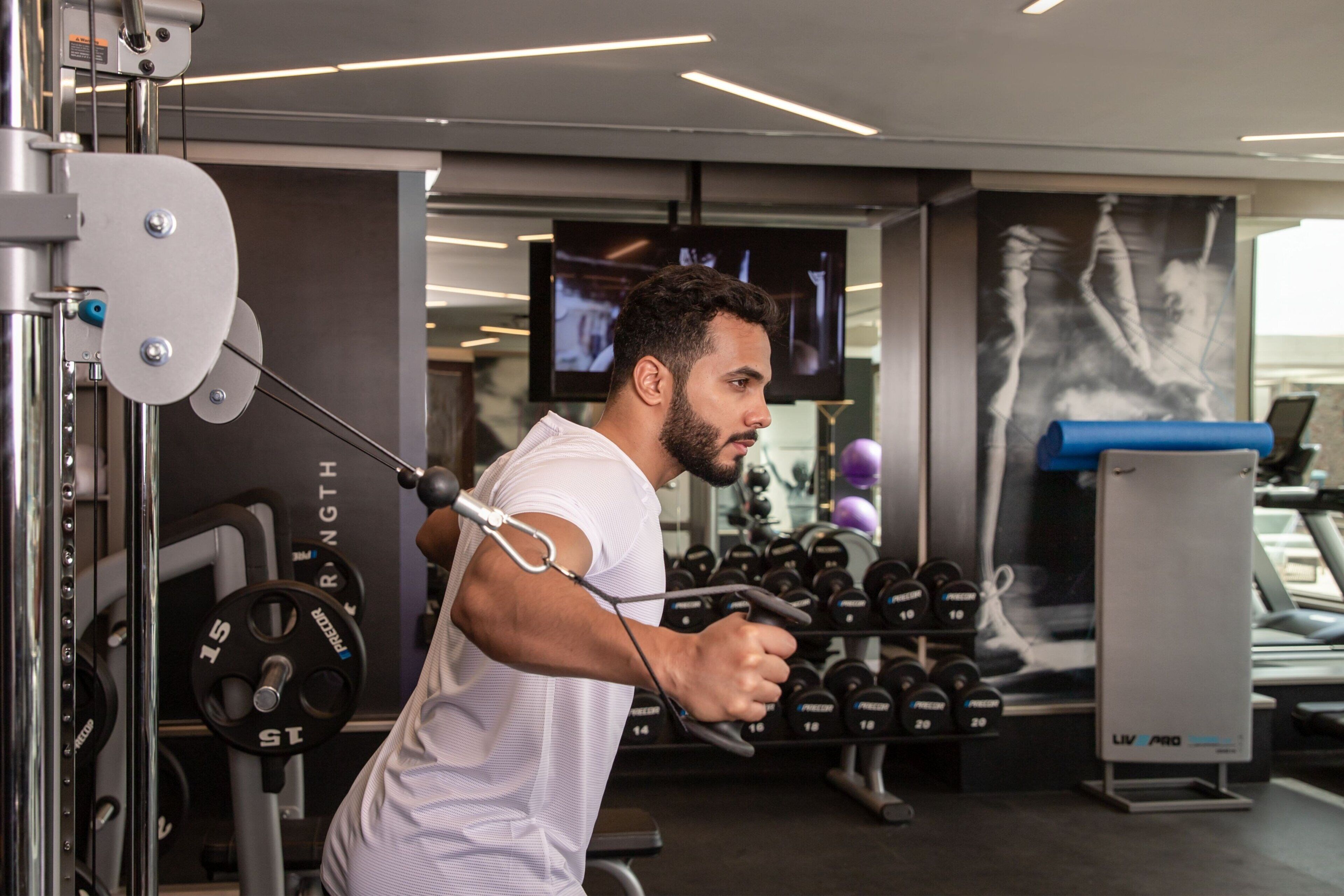 A gym with weightlifting equipment, a television screen, and a treadmill.