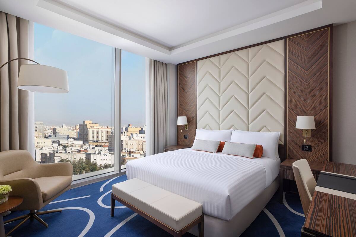 Une chambre d’hôtel avec un grand lit, un bureau, une chaise et une vue sur la ville.