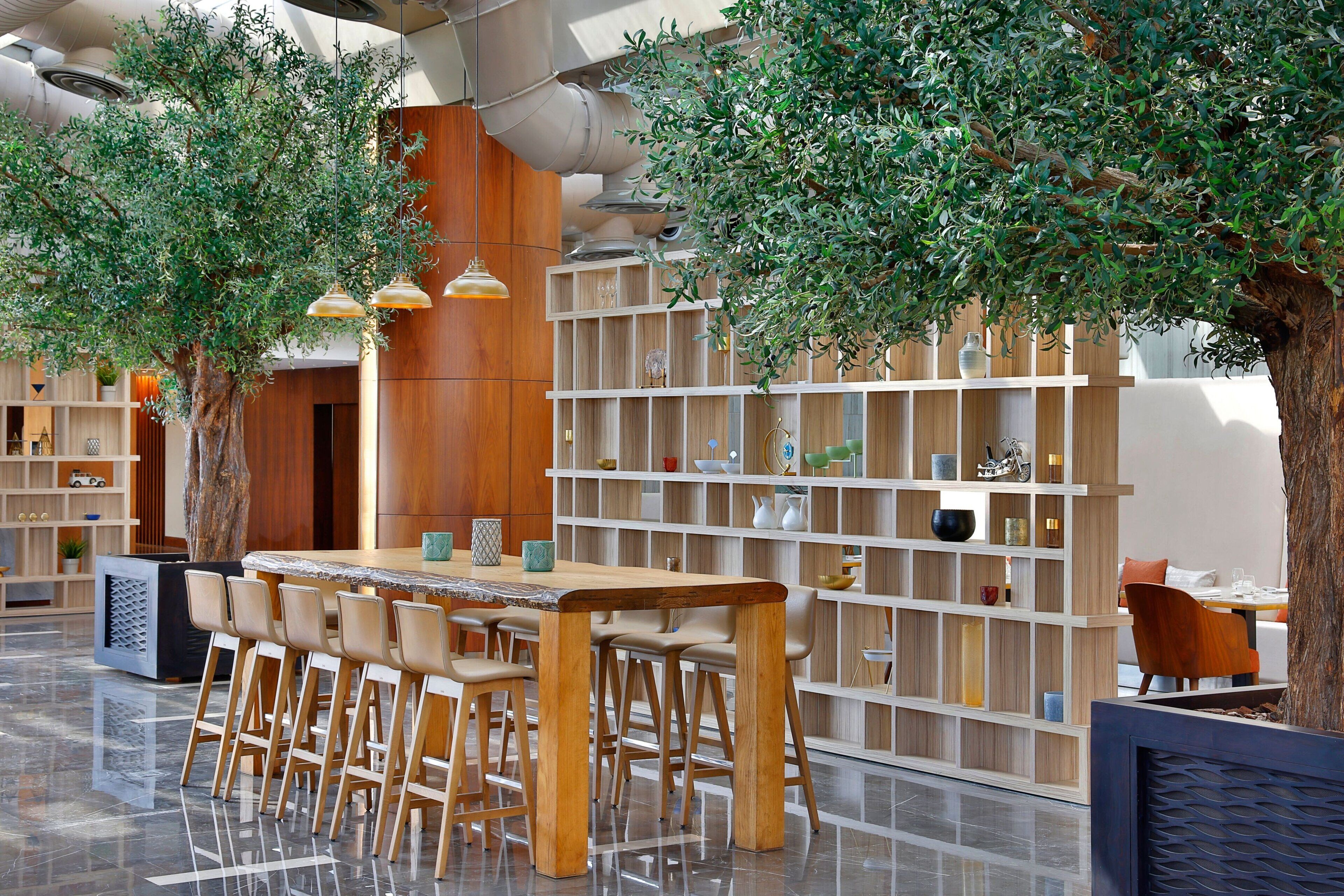 Een modern interieur met een houten bar, zitplaatsen en planken met decoratieve objecten.