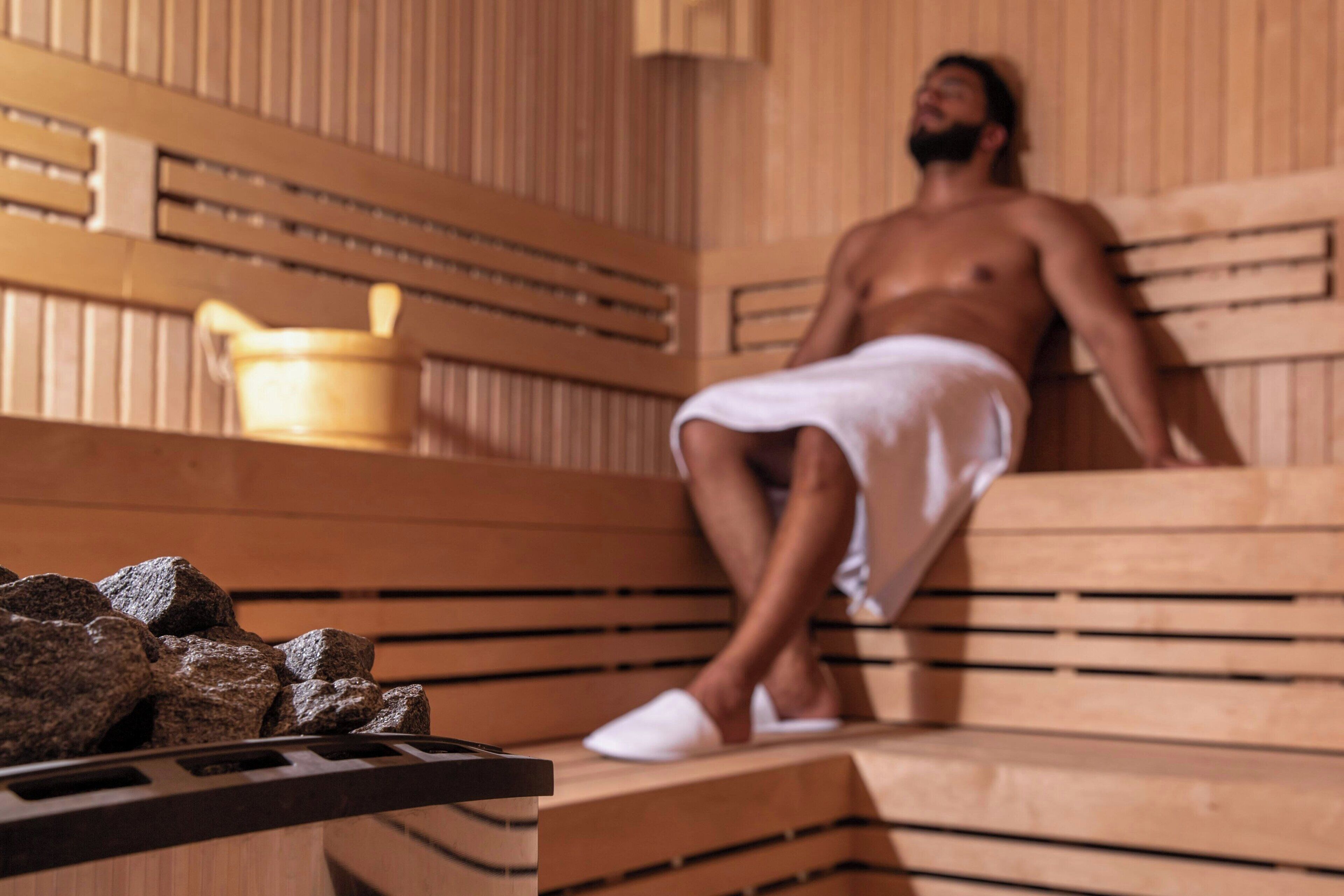 A sauna with wooden benches and a stone bench in the foreground.