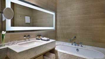 A modern bathroom with a large mirror, two sinks, a bathtub, and a towel rack.