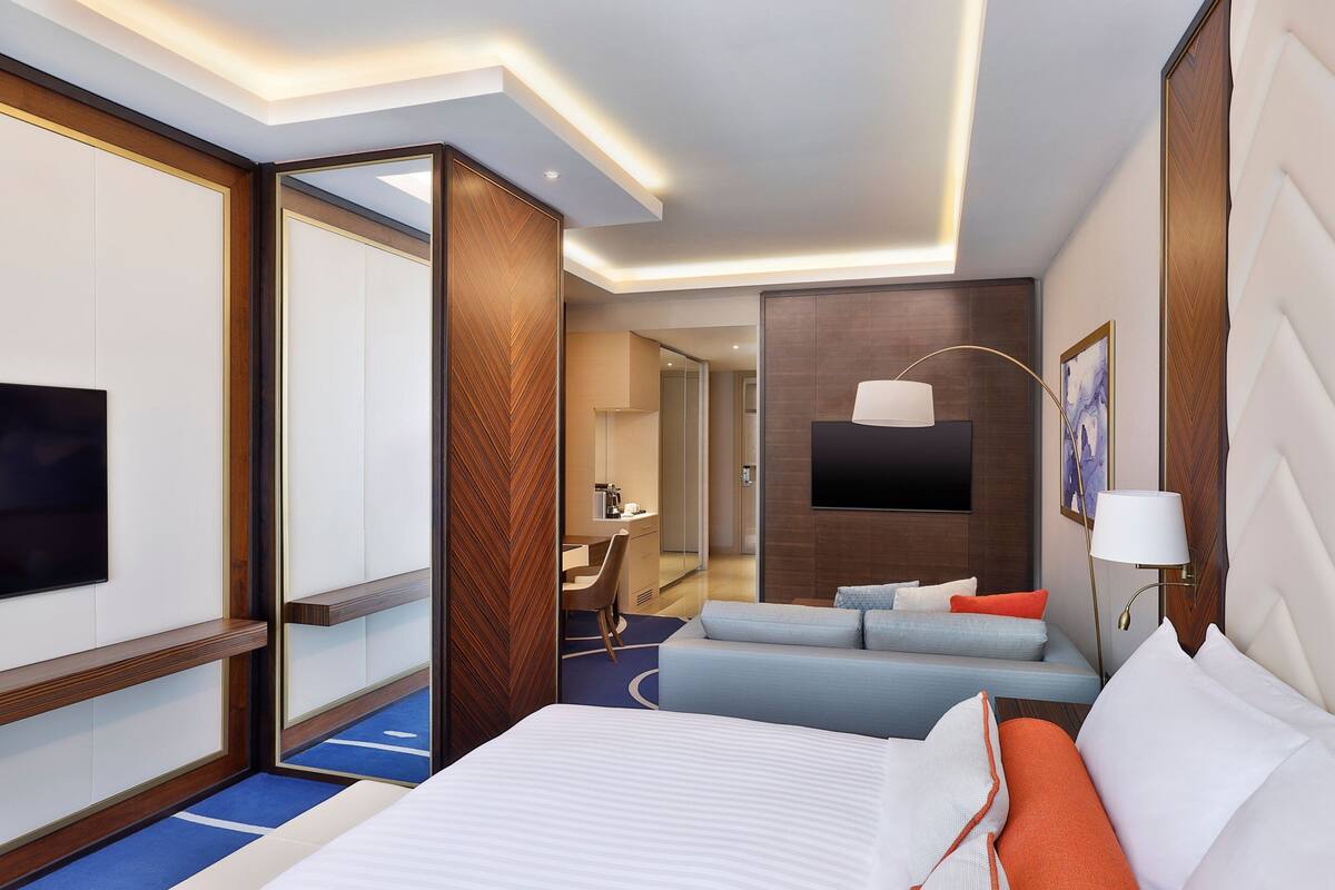 Une chambre d’hôtel moderne, dotée d’un grand lit, d’un canapé, d’un bureau et d’une télévision.