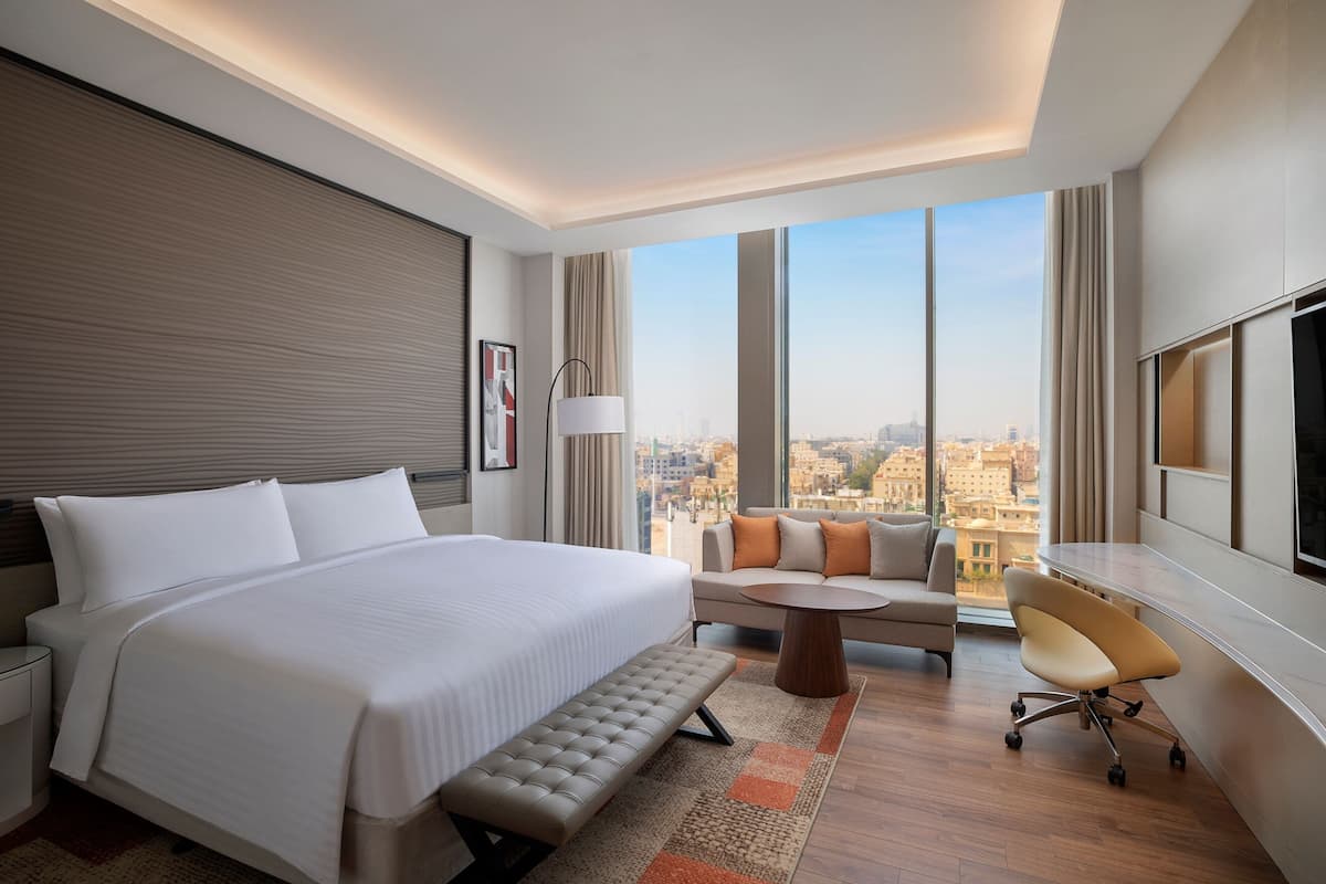Une chambre d’hôtel moderne, dotée d’un grand lit, d’un canapé, d’un bureau et offrant une vue sur la ville.