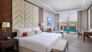 Une chambre d’hôtel moderne avec un grand lit, un bureau et une vue sur une piscine.