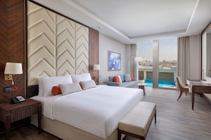 Habitación de hotel moderna con una cama grande, un escritorio y vistas a una piscina.