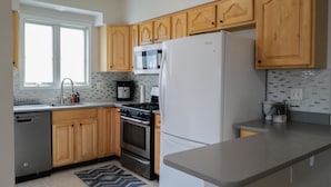 Una cocina moderna con armarios de madera, un refrigerador de acero inoxidable, un microondas y un lavavajillas.
