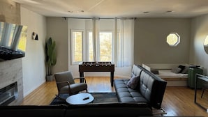 Una sala de estar moderna con un sofá, una mesa de fútbol y una cama.