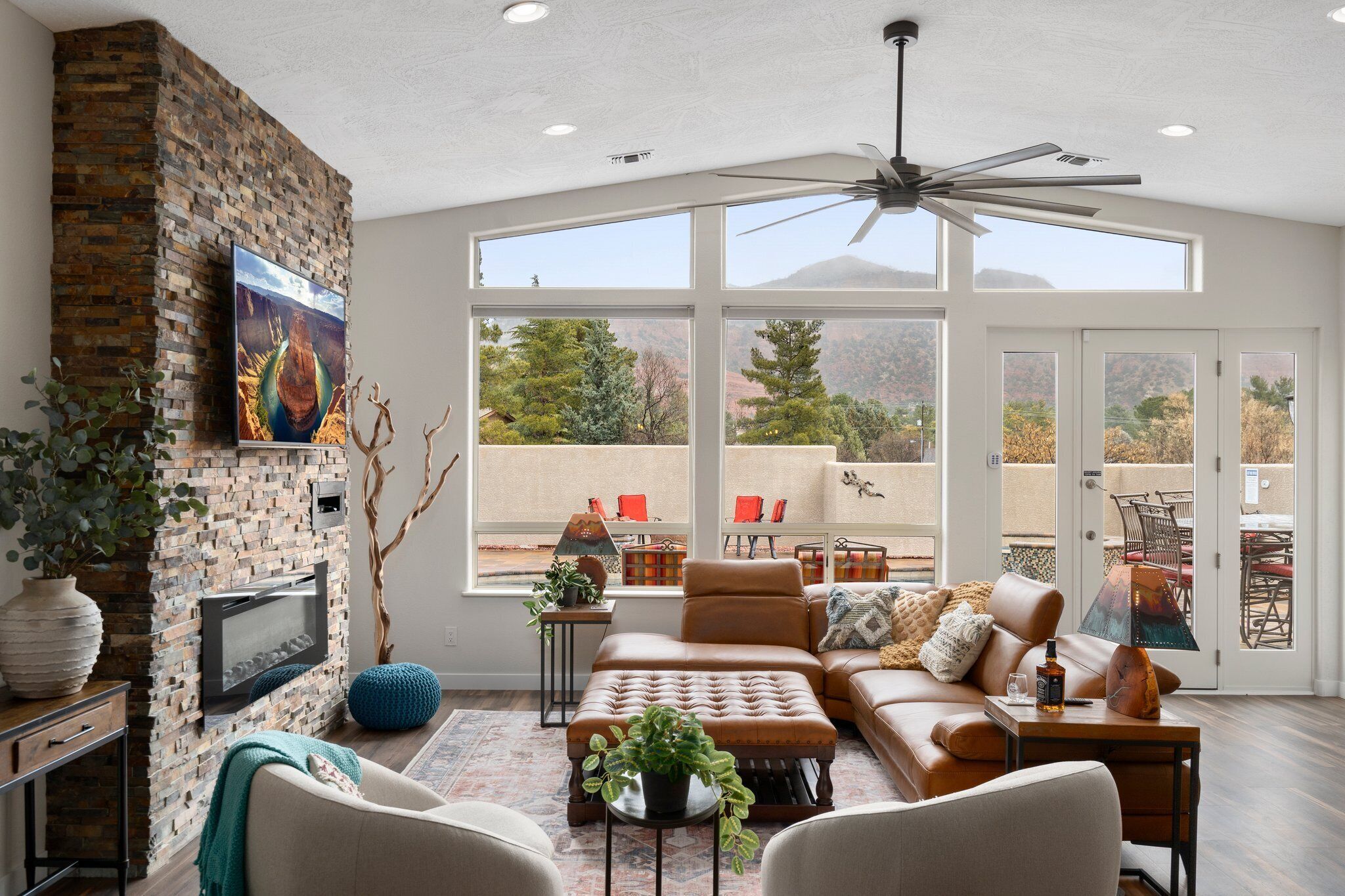 A spacious living room with a fireplace, comfortable seating, large windows, and a view of the outdoors.