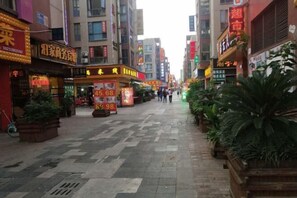 A bustling urban street with various shops and signs, including a prominent yellow storefront with a red sign.