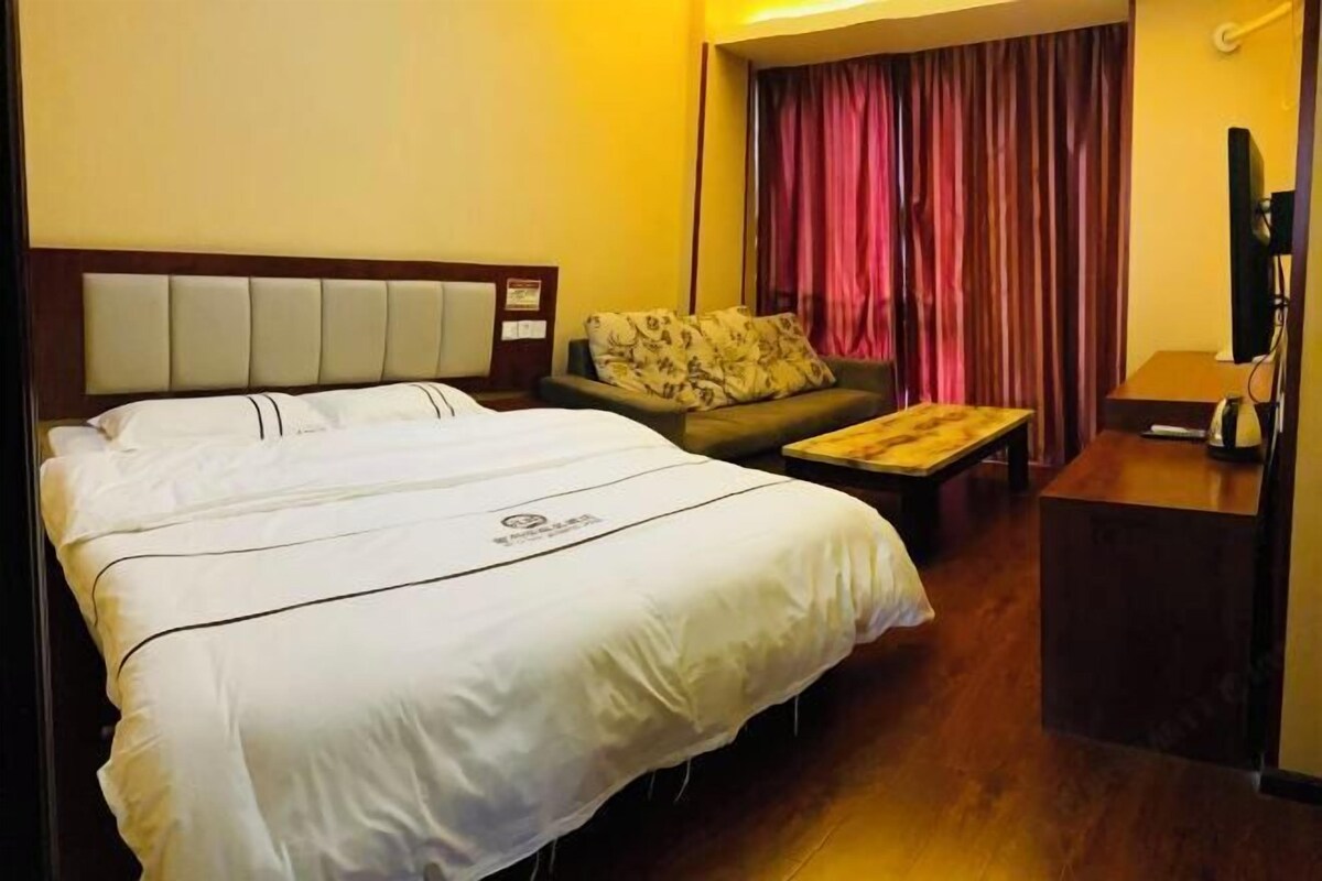 A hotel room with a large bed, a sofa, a small table, and a TV.