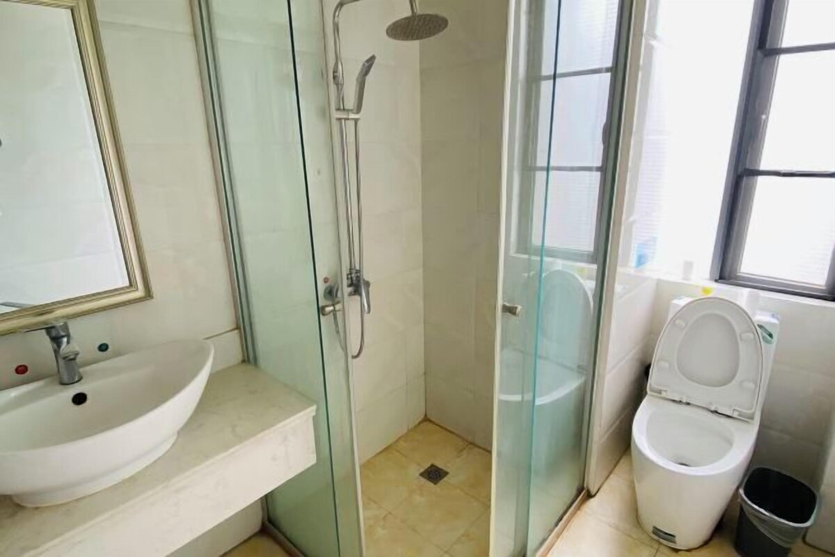 A bathroom with a glass-enclosed shower, a sink, and a toilet.