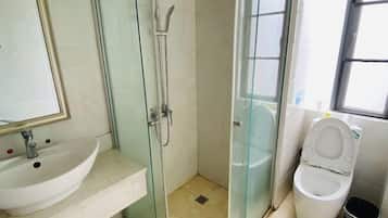 A bathroom with a glass-enclosed shower, a sink, and a toilet.