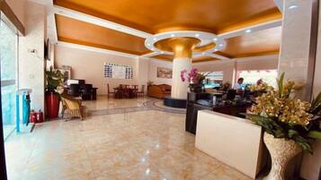 A hotel lobby with a reception desk, seating area, and a large decorative column.
