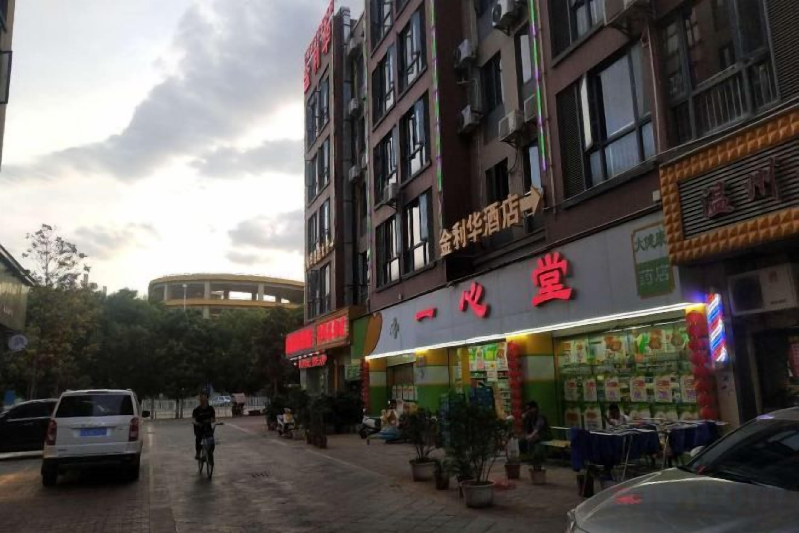 A street with shops, including a brightly lit store with red signage.