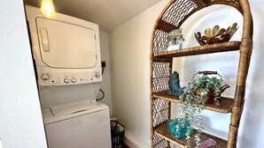 Ein Waschbereich mit Waschmaschine und Trockner, einem Korbschrank mit Dekoration und einer Lampe über dem Trockner.