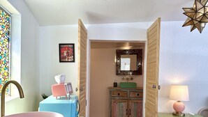 Ein Badezimmer mit einem rosa Waschbecken, einem alten Fernseher, einem grünen Spülbecken und einem Spiegel darüber.