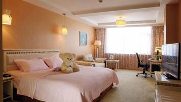 A hotel room with a large bed, a desk, a chair, a television, and a window with curtains.