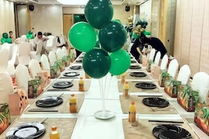 A long banquet table with chairs, balloons, and table settings.