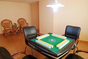 A room with a pool table, two black chairs, a small table with a plant, and two wicker chairs. - Yuanli International Hotel (Suichang)
