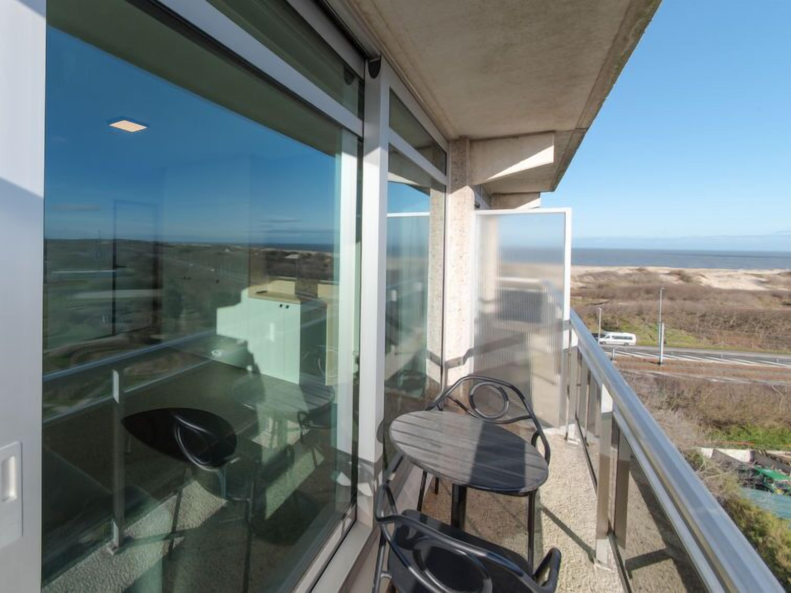 Un balcon avec vue sur la mer, une table et deux chaises.