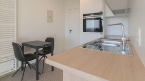 A small kitchenette with a sink, a stove, and a dining area with a table and chairs. - Astrid 802 with parking by Interhome (Bredene)