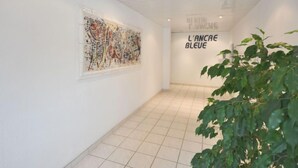 A hallway with a large abstract painting on the left and a sign reading "L'ANCARE BLEUE" on the right. - Ancre Bleue by Interhome (Cavalaire)